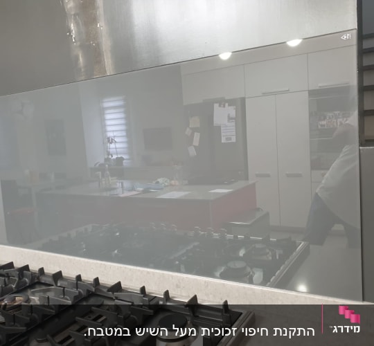 זכוכית מחזירה השתקפות של מטבח מודרני